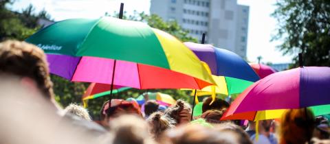 Regenbogenfarbene Regenschirme mit Helios-Logo beim Christopher-Street-Day in Berlin.
